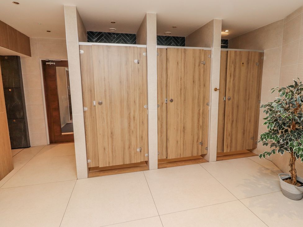 A changing room with wooden doors and a plant at Honeymug in Branton near Powburn