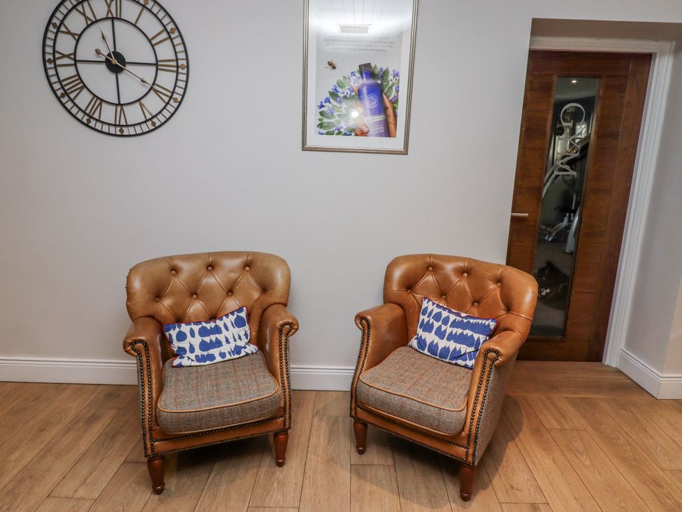 A living room with armchairs and wall clock at Honeymug in Branton near Powburn