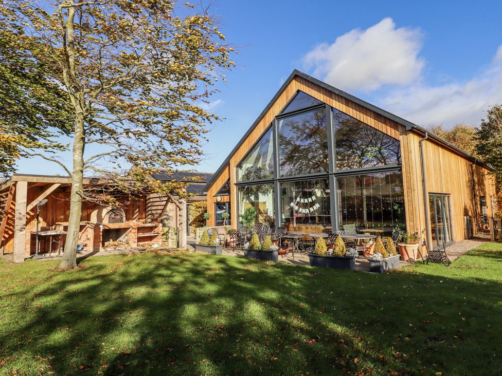 A house with large windows and outdoor seating at Honeymug in Branton near Powburn