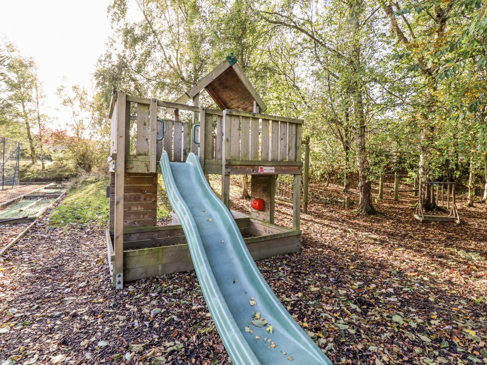 A playground with a slide and wooden structure in a wooded area at Honeymug in Branton near Powburn