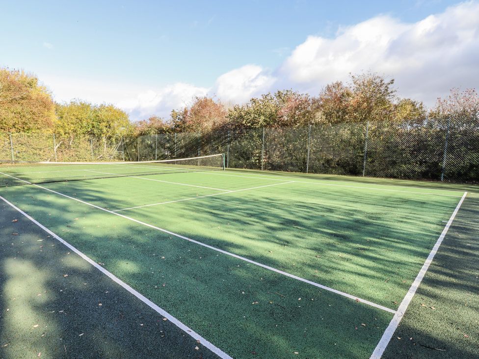 A tennis court with a net and fencing at Honeymug in Branton near Powburn
