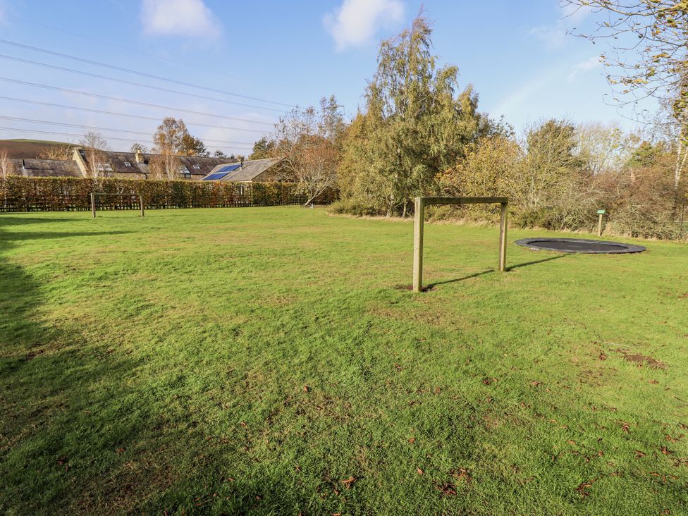 A garden with grass and a trampoline at Honeymug in Branton near Powburn