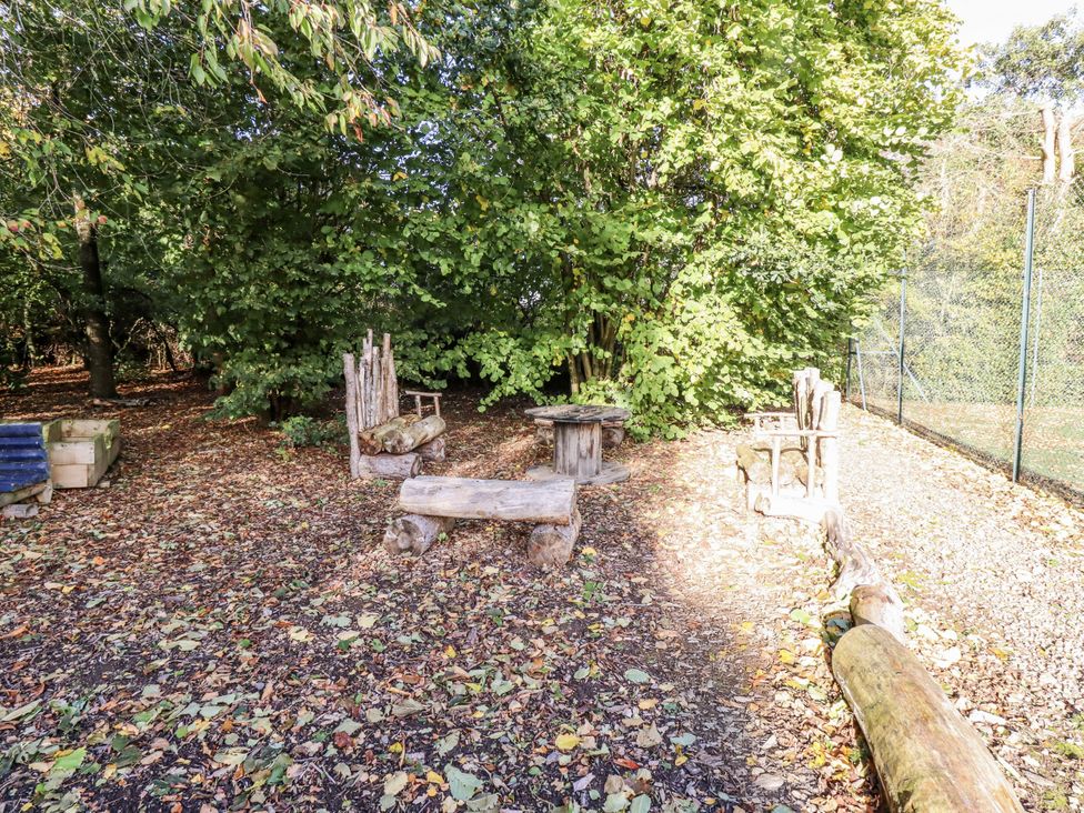 An outdoor seating area with wooden furniture and trees at Honeymug in Branton near Powburn