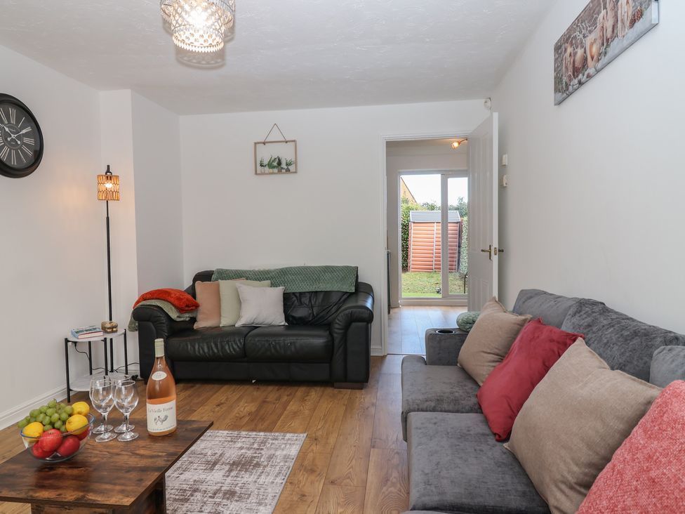 A living room with sofas, coffee table, and door access to the garden at The Cosy View in Paignton