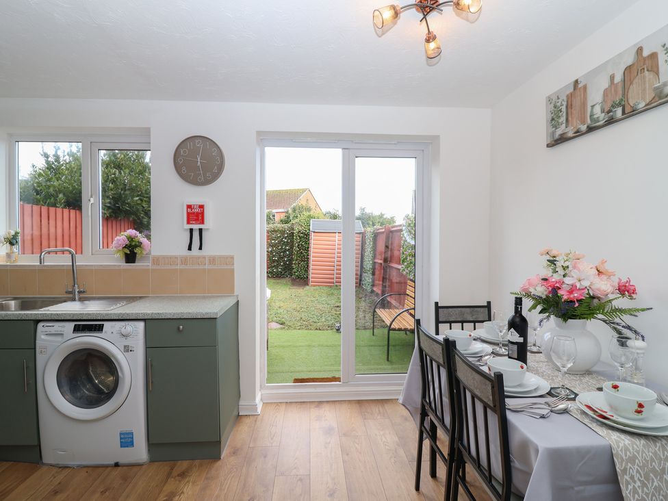 A kitchen with a washing machine and dining table at The Cosy View in Paignton