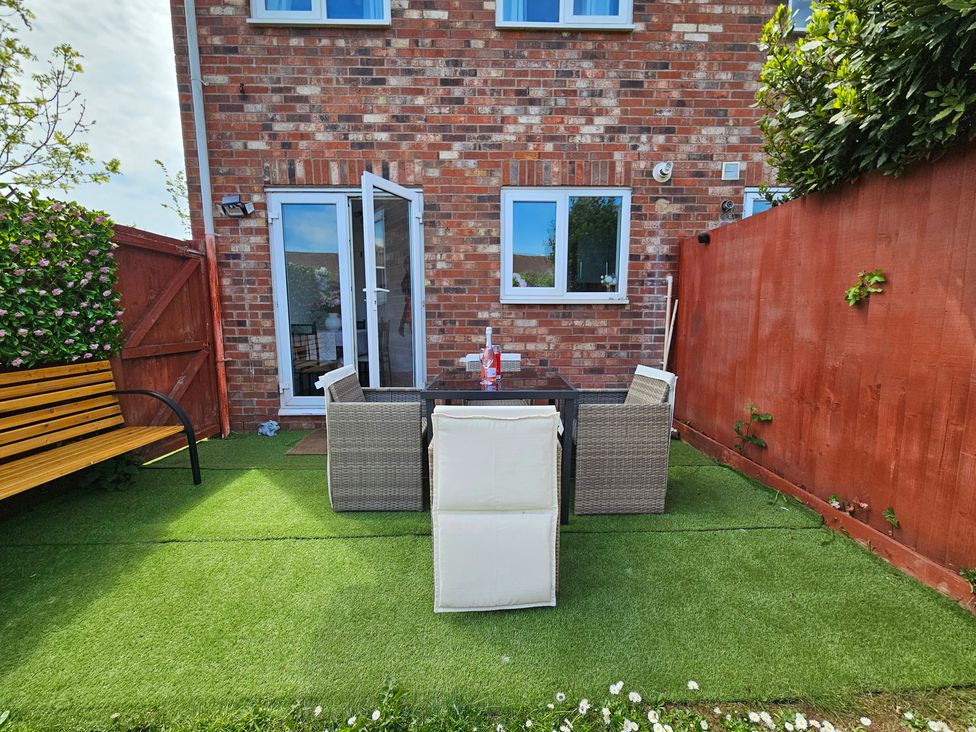 A garden with table, chairs, and a bench at The Cosy View in Paignton