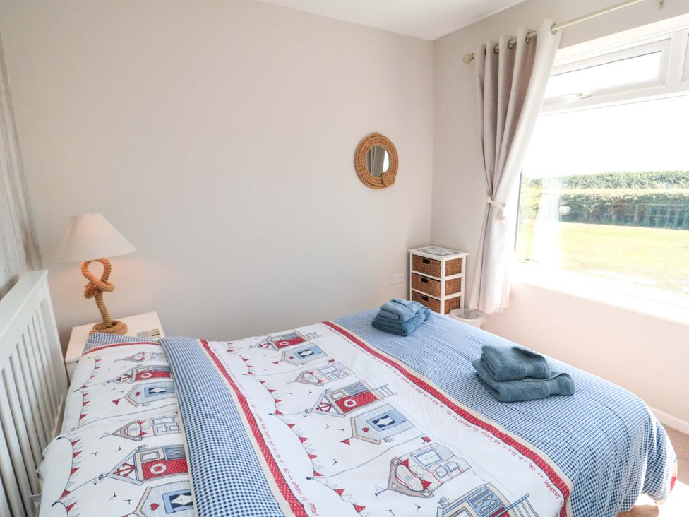 A bedroom with a bed, lamp, and storage unit at Beach House