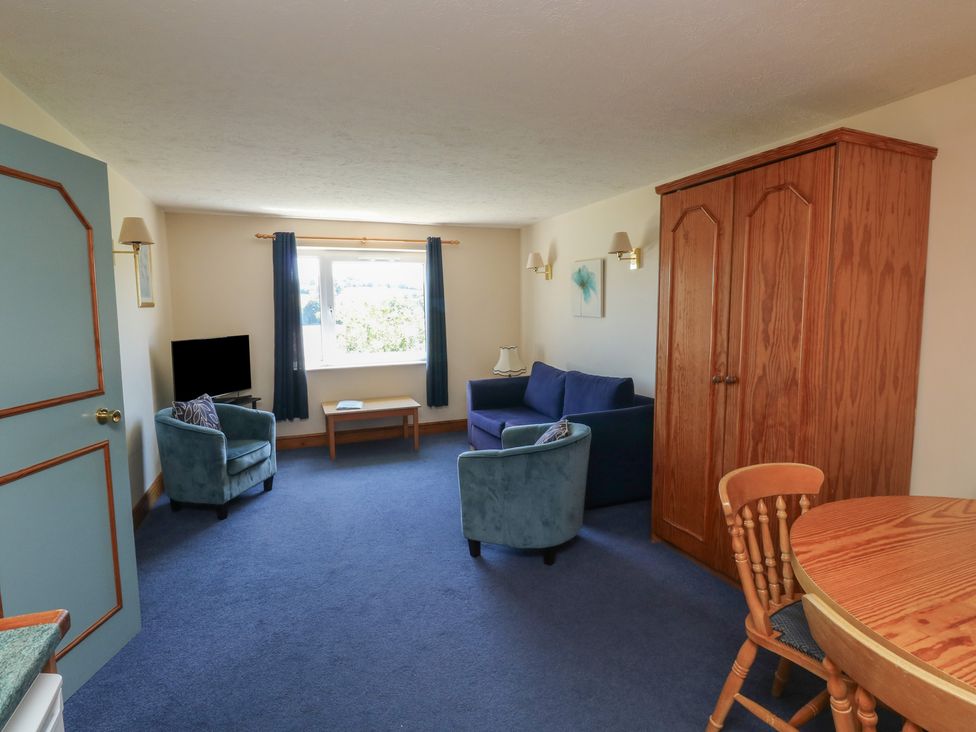 A living room with a sofa, armchair, and a table at Teal in Newton Abbot