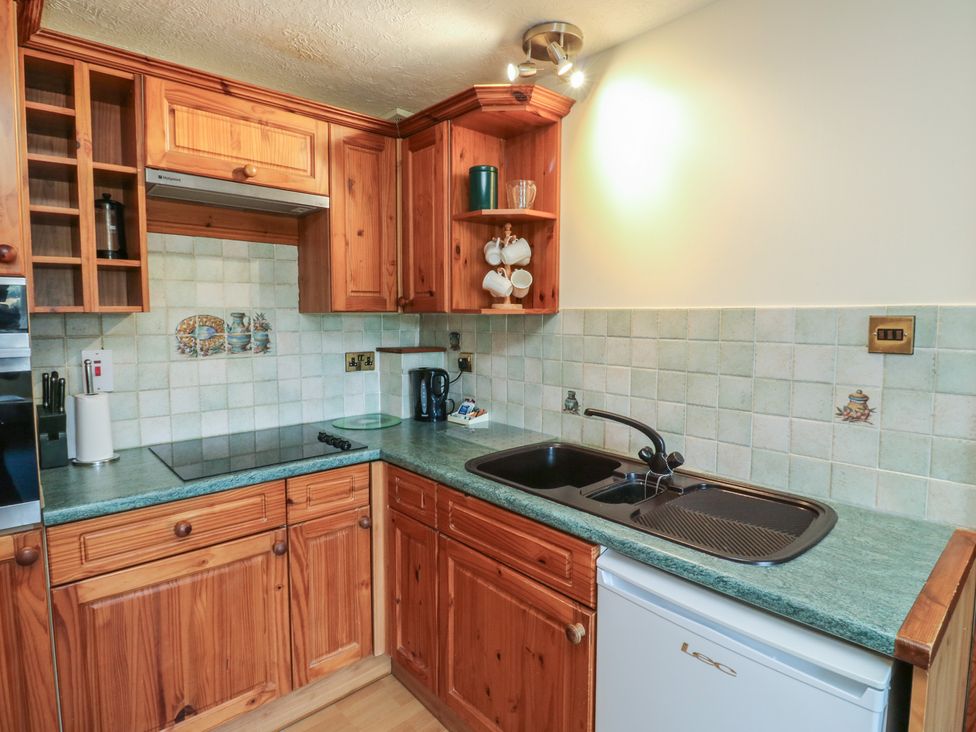 A kitchen with wooden cabinets and a sink at Teal in Newton Abbot