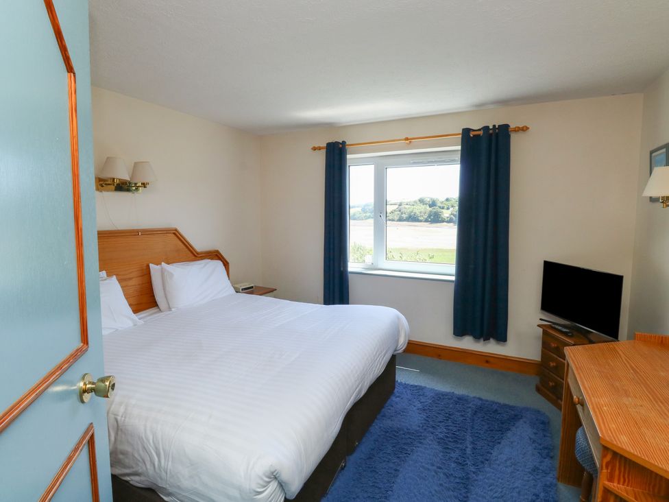 A bedroom with a bed, desk, and television at Teal in Newton Abbot