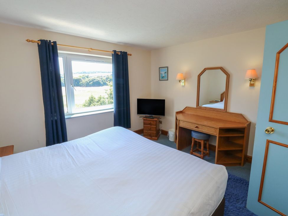 A bedroom with a bed, television, and dressing table at Teal in Newton Abbot