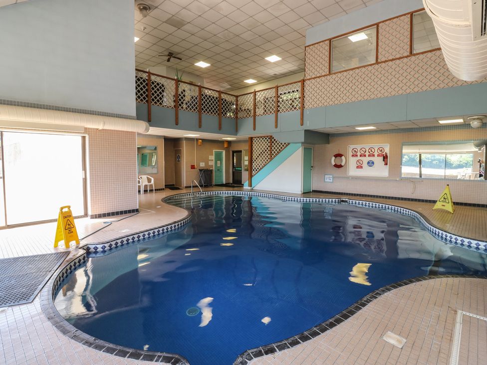 An indoor pool with seating and a caution sign at Teal in Newton Abbot