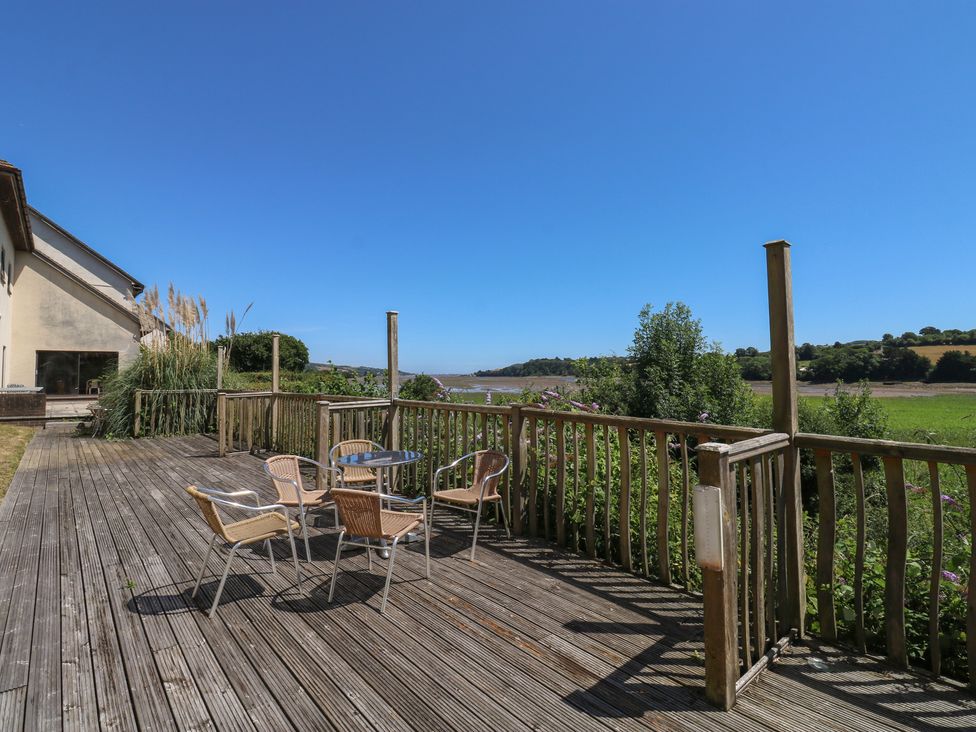 An outdoor area with a deck, chairs, and a table at Teal in Newton Abbot