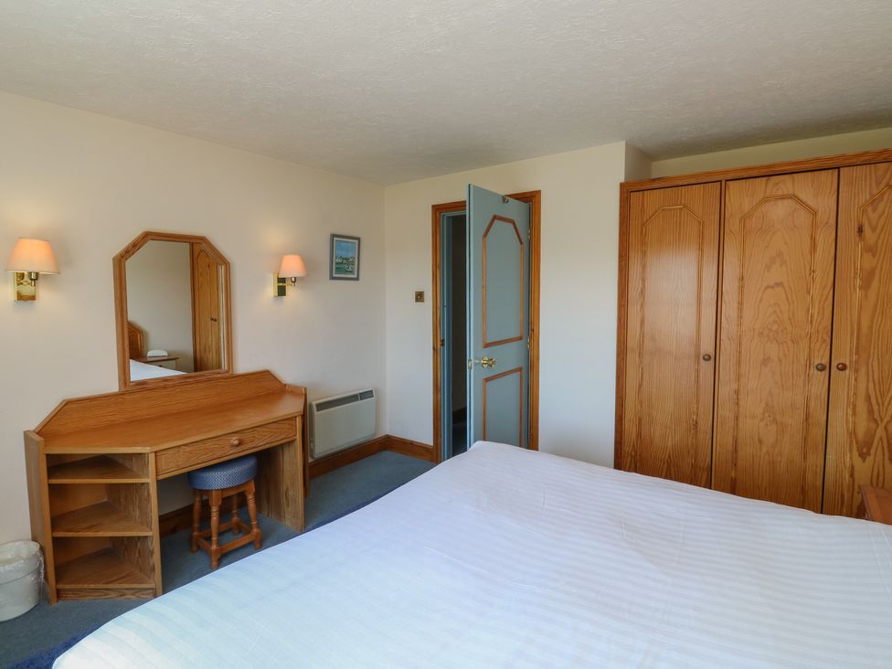 A bedroom with a bed, wardrobe, mirror, desk and chair at Nightjar in Newton Abbot