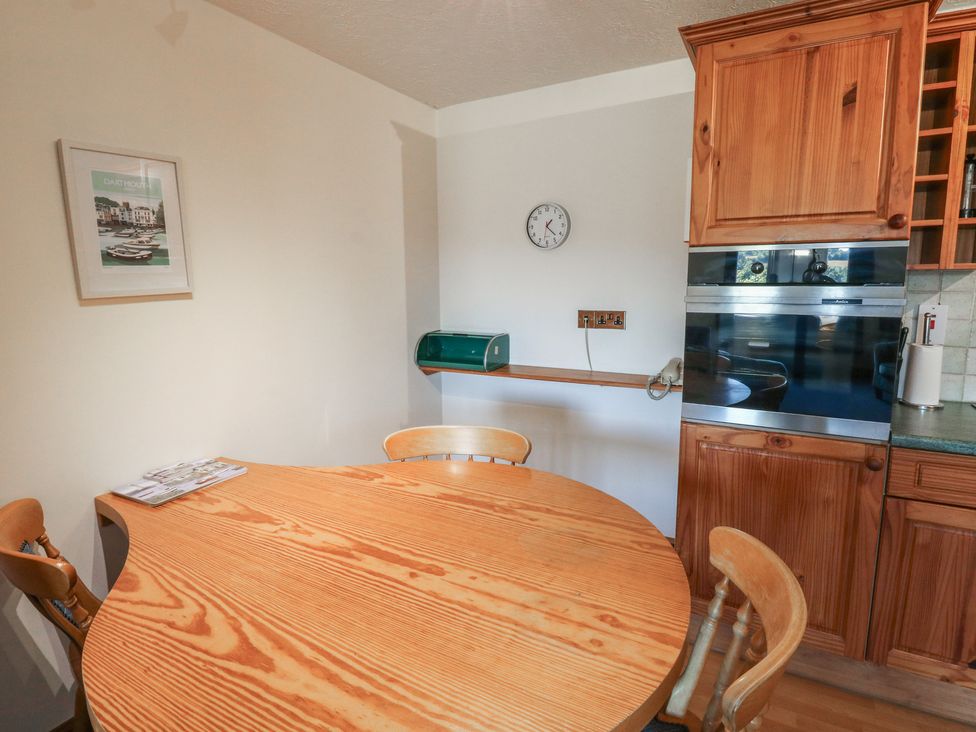 A kitchen with a round table and wooden cabinets at Swift in Newton Abbot
