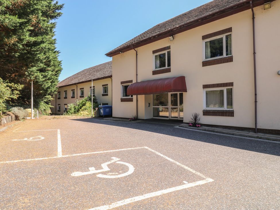 An outdoor area with a building entrance and parking spaces at Swift in Newton Abbot