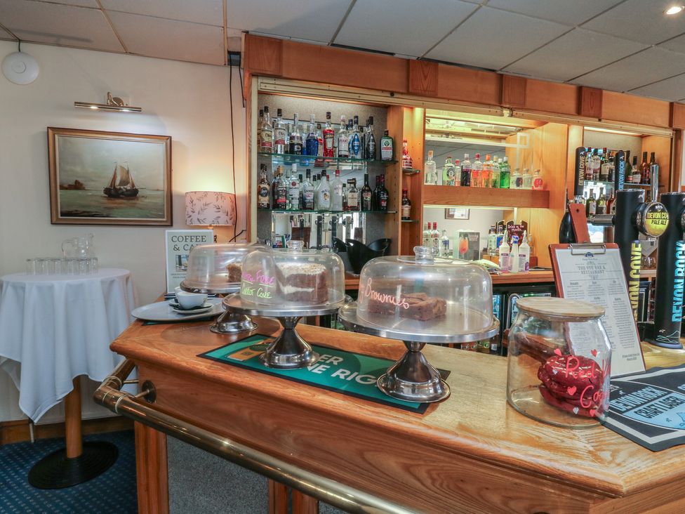 A bar counter with cake stands and shelves of bottles at Swift in Newton Abbot