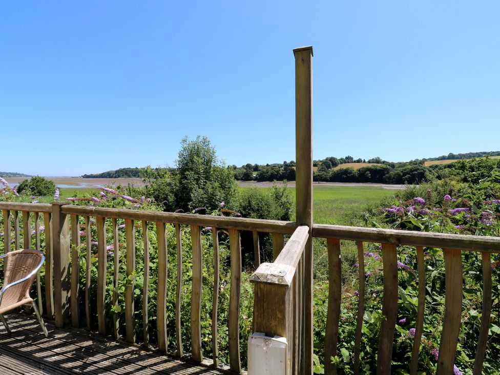 A view from a balcony overlooking a grassy area and trees at Swift in Newton Abbot