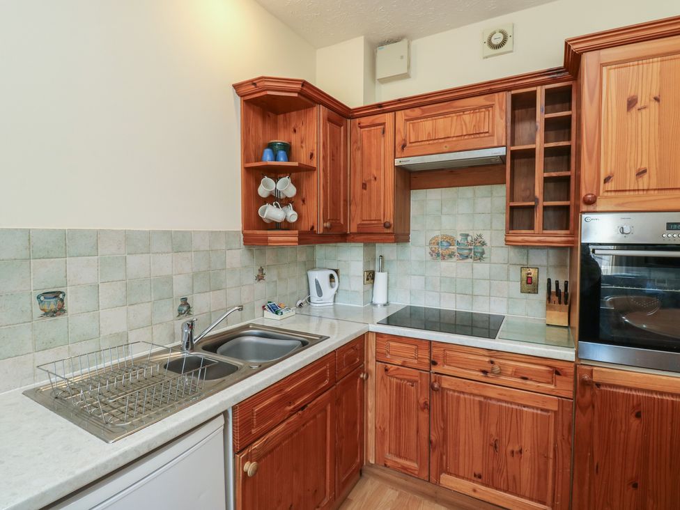 A kitchen with wooden cabinets and appliances at Egret in Newton Abbot