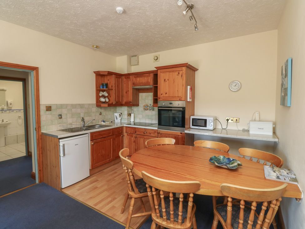 A kitchen with wooden units and a dining table at Avocet in Newton Abbot