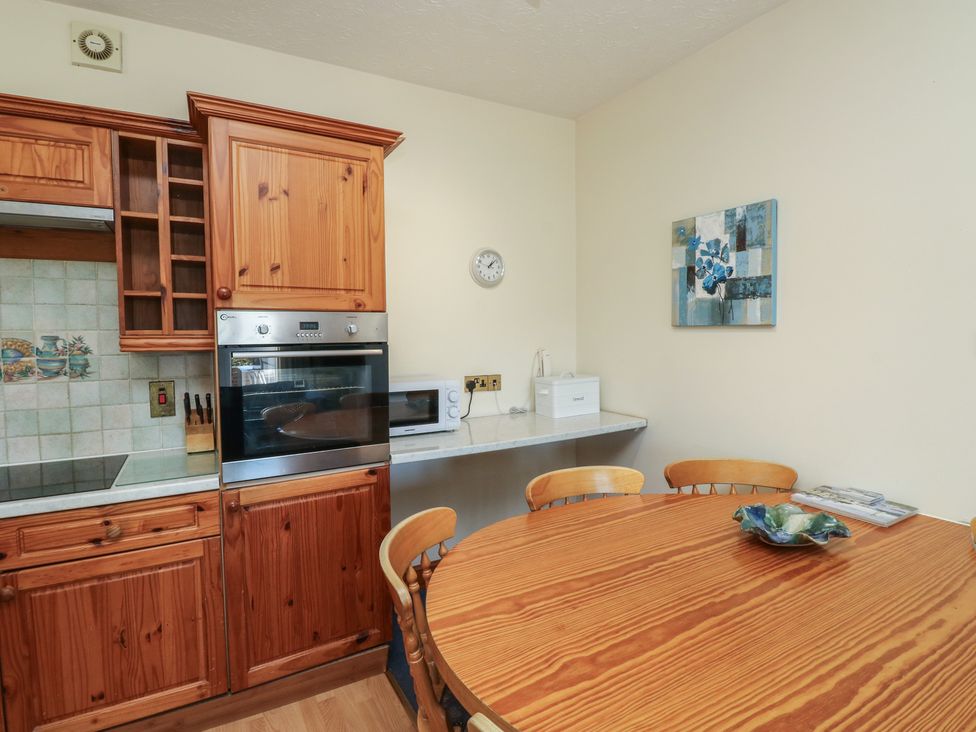 A kitchen with wooden cabinets and a dining table at Avocet in Newton Abbot