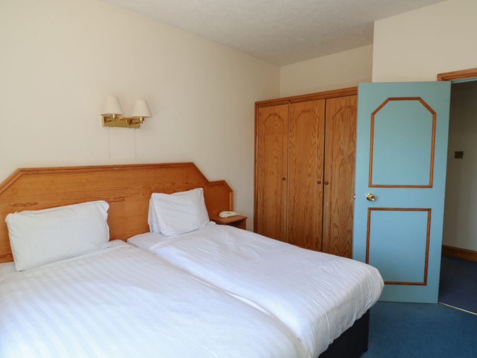 A bedroom with two beds and a wardrobe at Avocet in Newton Abbot
