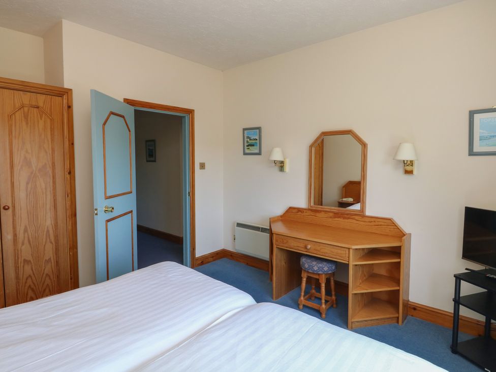 A bedroom with a bed, wardrobe, and vanity at Avocet in Newton Abbot