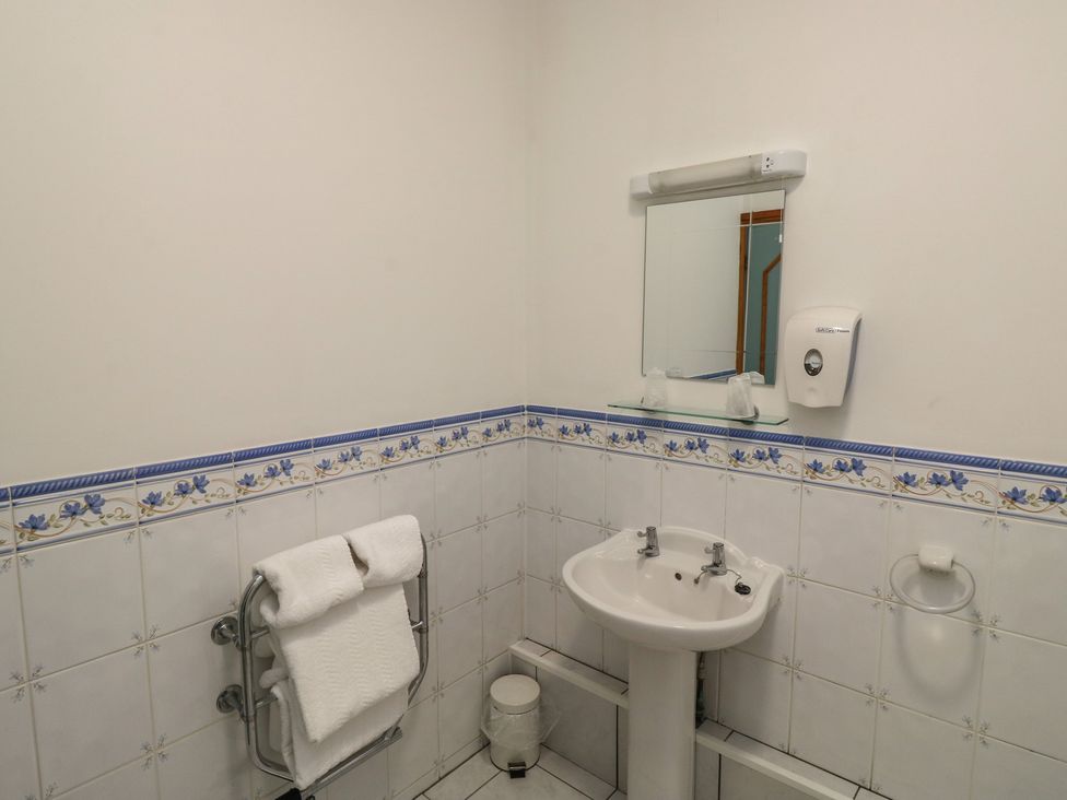 A bathroom with a sink, mirror, towel rack and soap dispenser at Avocet in Newton Abbot