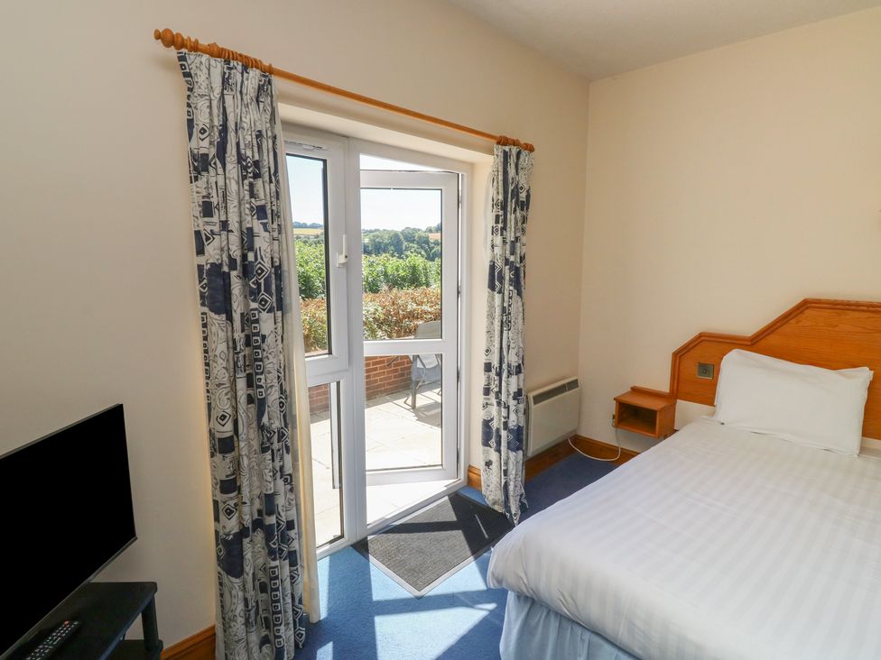 A bedroom with a bed and a door leading outside at Avocet in Newton Abbot