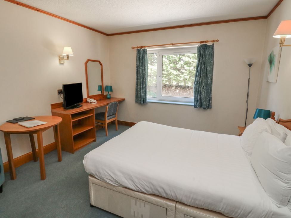 A bedroom with a bed, desk and television at Sycamore in Newton Abbot