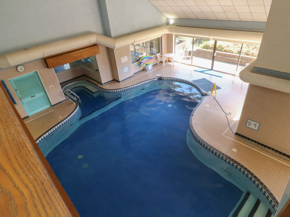 An indoor pool area with a swimming pool and safety signs at Sycamore in Newton Abbot