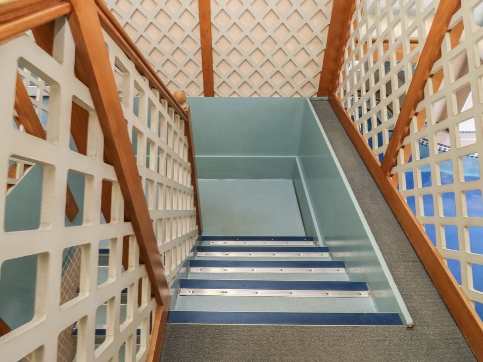 A staircase with a handrail and lattice work at Sycamore in Newton Abbot