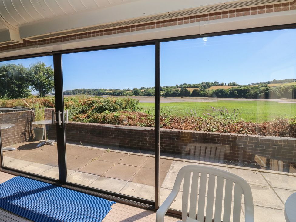 A conservatory with sliding glass doors and a view of nature at Sycamore Newton Abbot