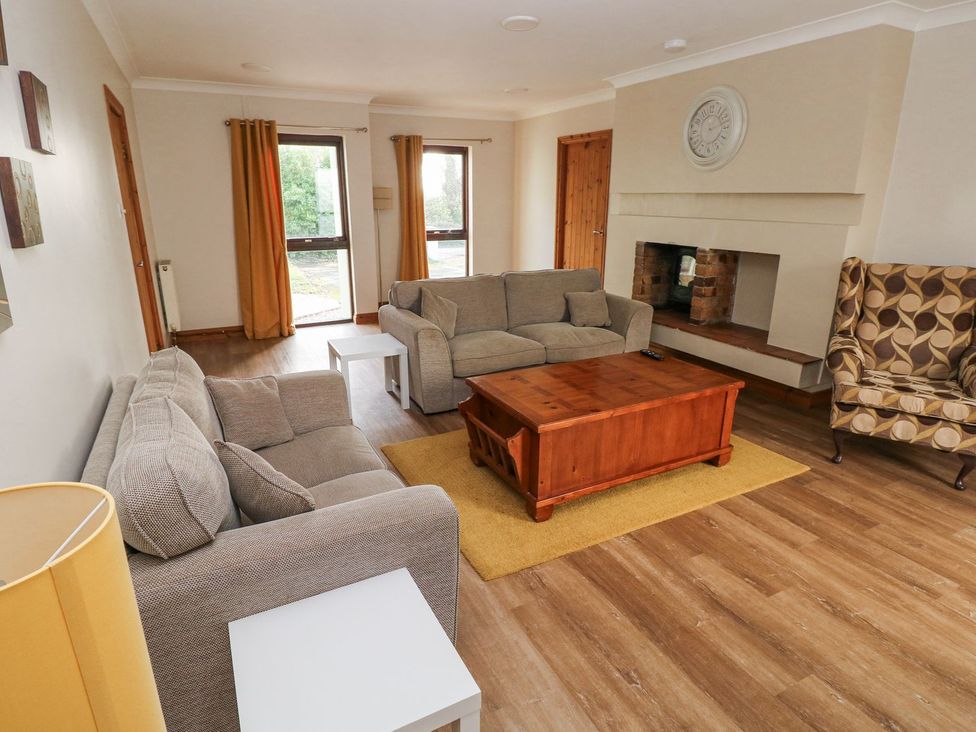 A living room with a sofa, coffee table, and armchair at Tig Bhan in Narberth