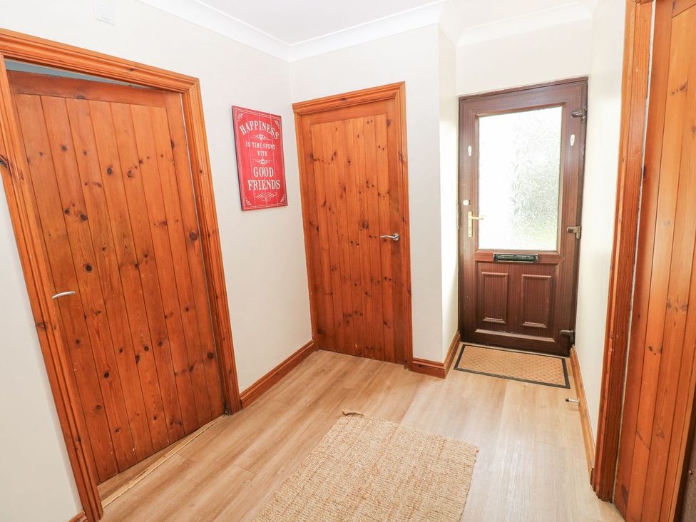 A hallway with wooden doors and a front door at Tig Bhan in Narberth