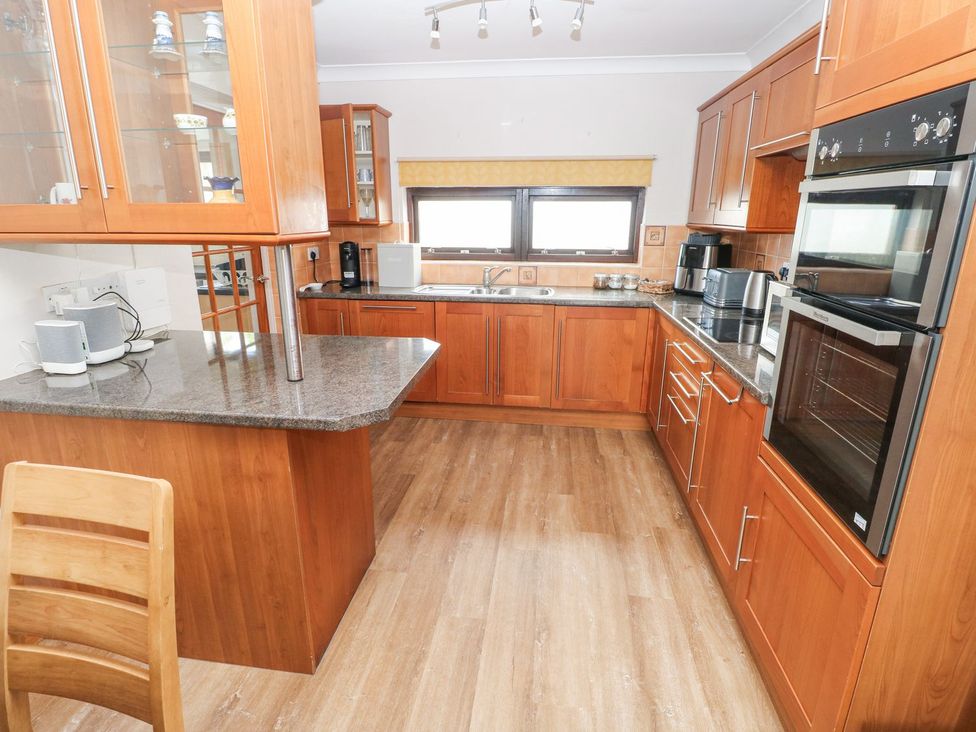 A kitchen with wooden cabinets and appliances at Tig Bhan in Narberth