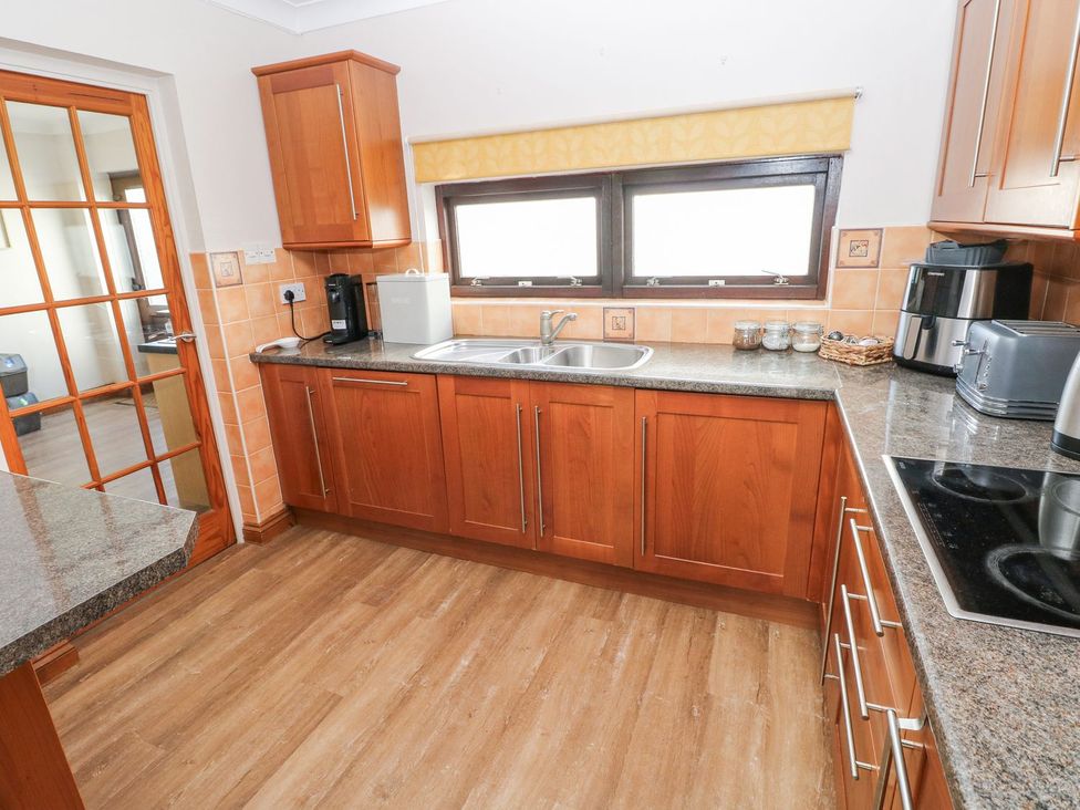 A kitchen with wooden cabinets and countertop at Tig Bhan in Narberth