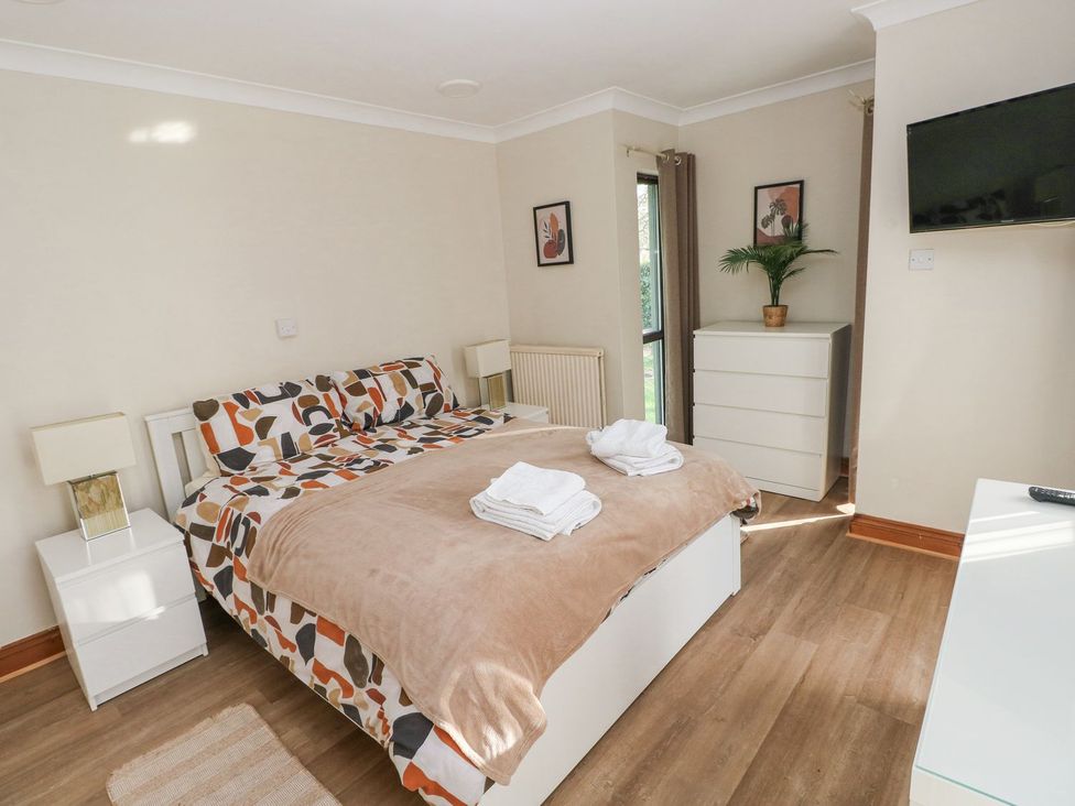 A bedroom with a bed and dresser at Tig Bhan in Narberth