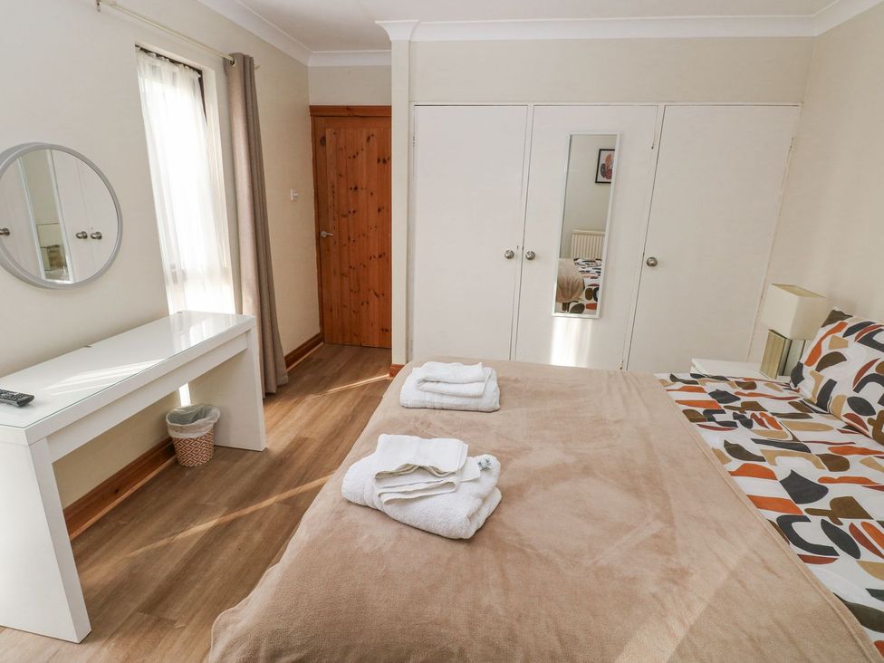 A bedroom with a bed and a dressing table at Tig Bhan in Narberth