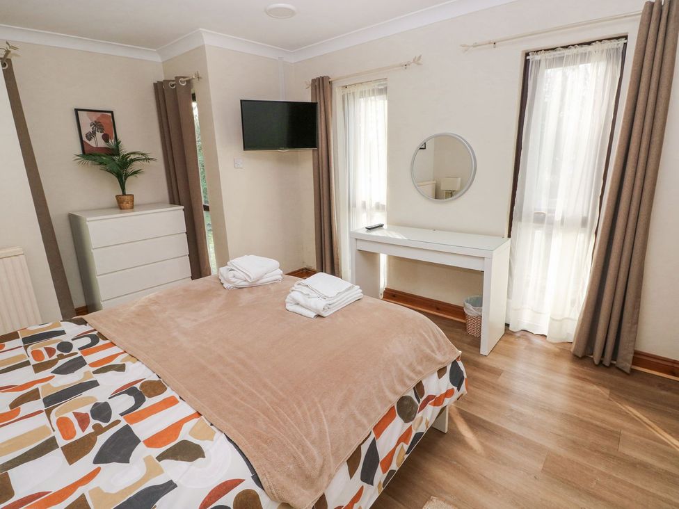 A bedroom with a bed and a dressing table at Tig Bhan in Narberth