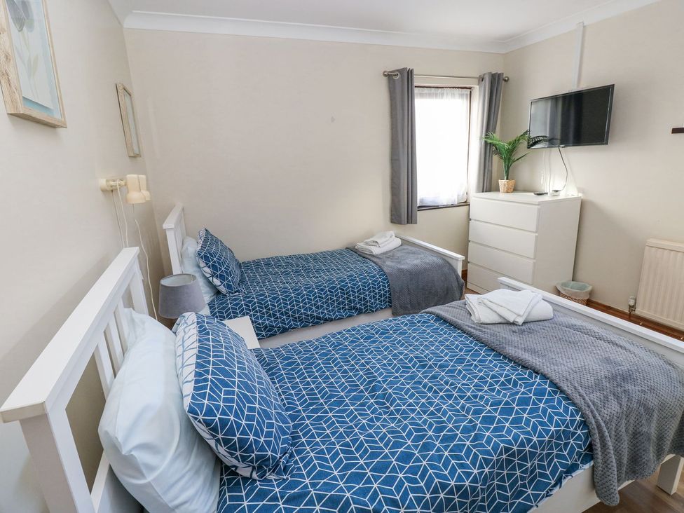 A bedroom with two beds, a dresser and a television at Tig Bhan in Narberth