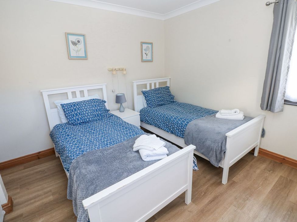 A bedroom with twin beds and nightstand at Tig Bhan in Narberth