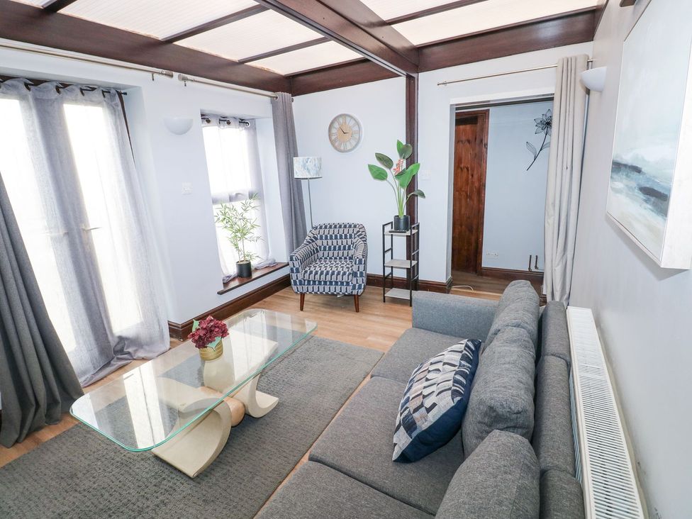 A living room with a sofa, coffee table, and plant at Cuddfan in Narberth
