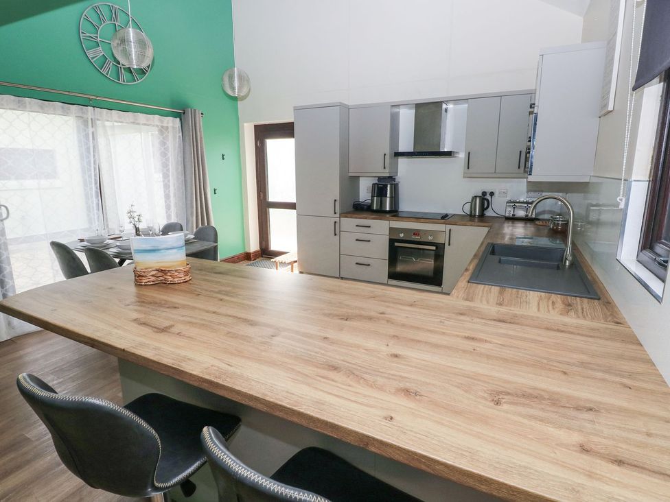 A kitchen with a bar area and appliances at Cuddfan in Narberth