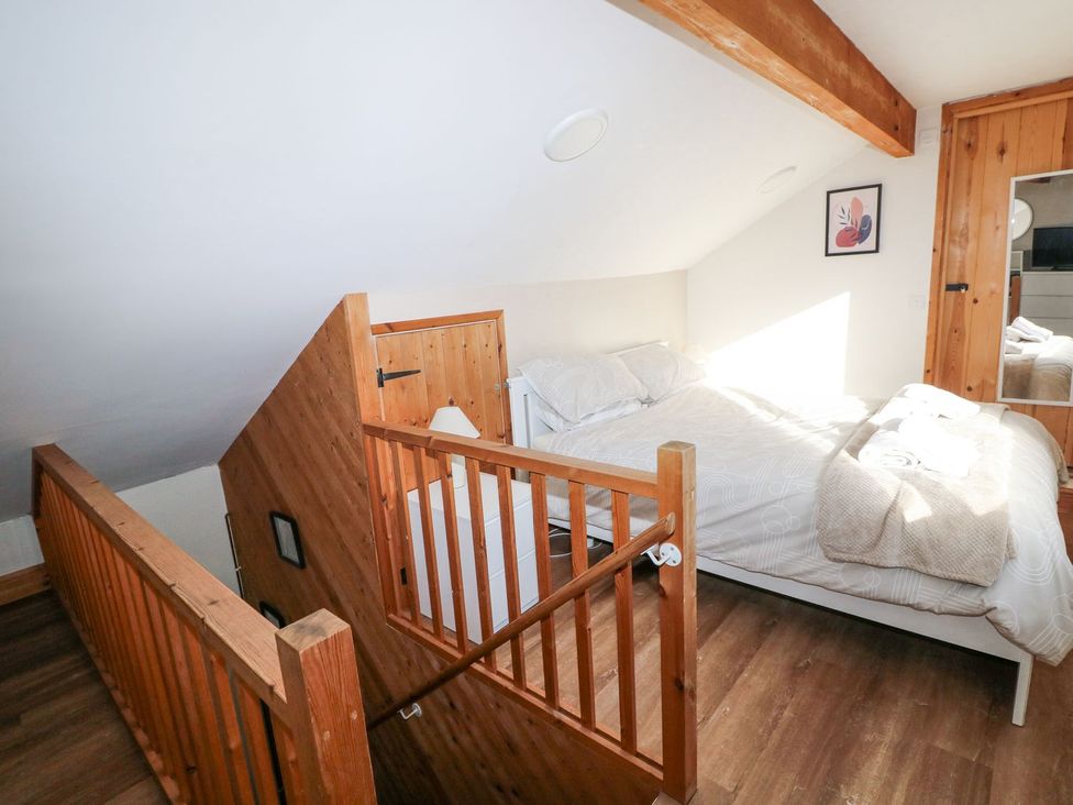 A loft bedroom with a bed and wooden railing at Cuddfan Narberth