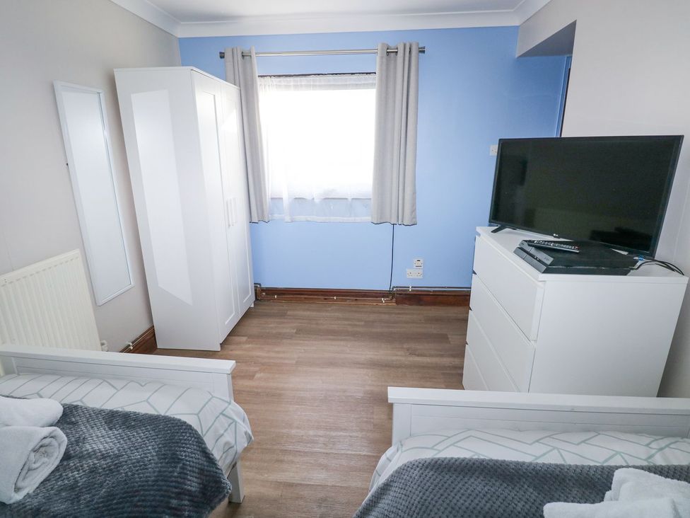 A bedroom with a bed wardrobe dresser and tv at Cuddfan Narberth