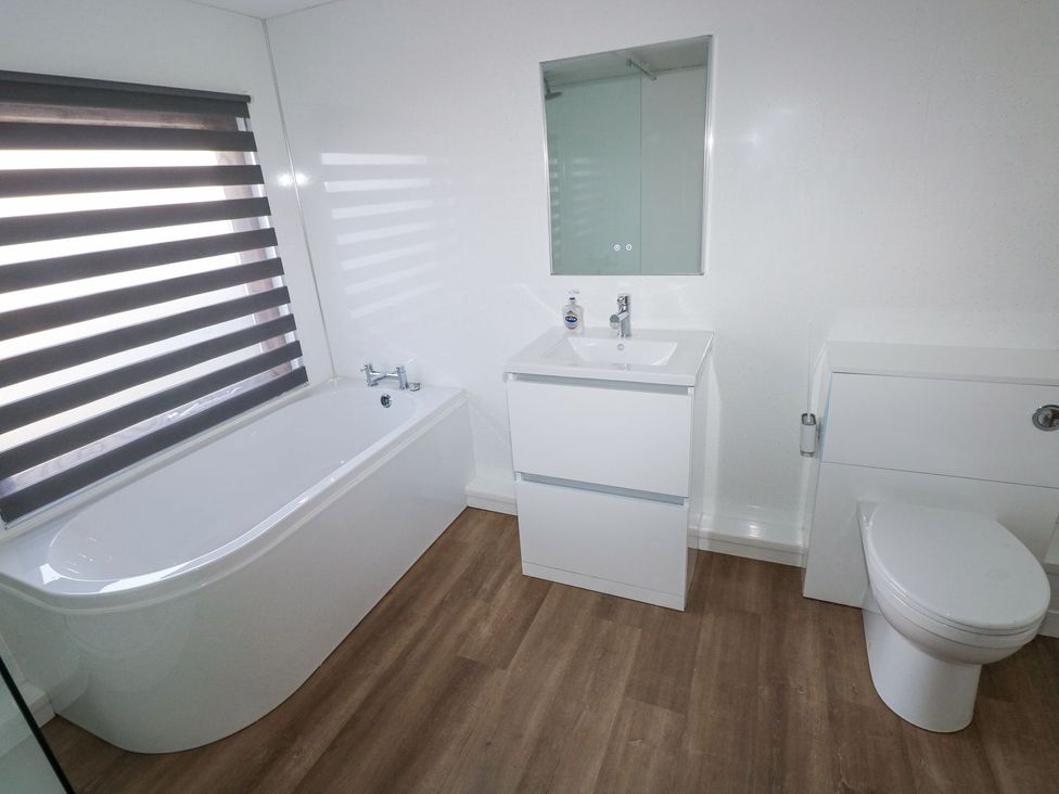 A bathroom with a bath tub, sink and toilet at Cuddfan in Narberth
