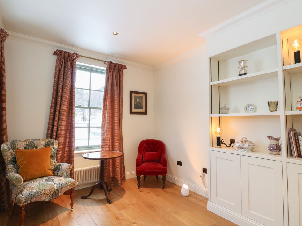 A sitting room with an armchair and a small table at Schiehallion House in Pitlochry
