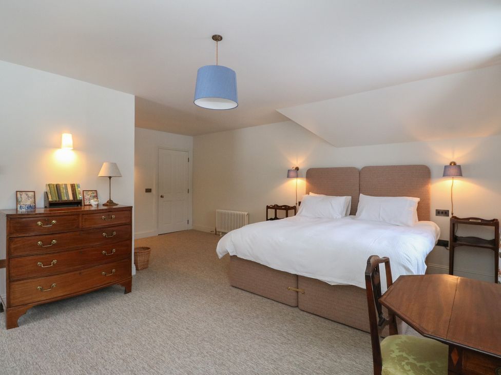 A bedroom with a bed, chest of drawers, and table at Schiehallion House in Pitlochry