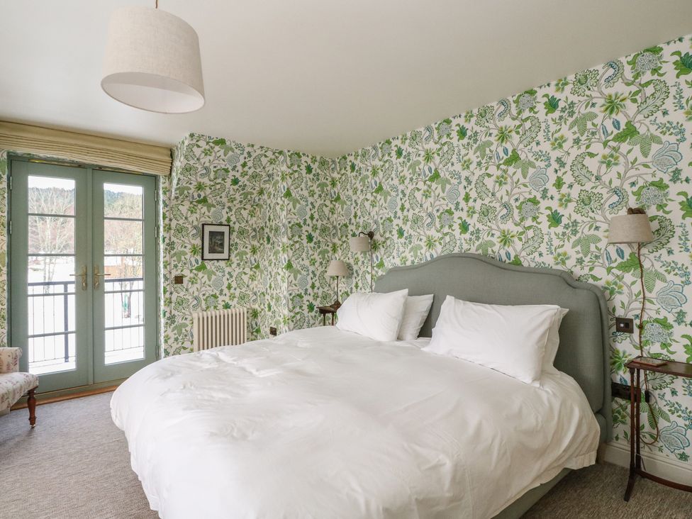 A bedroom with a bed and doors to a balcony at Schiehallion House in Pitlochry